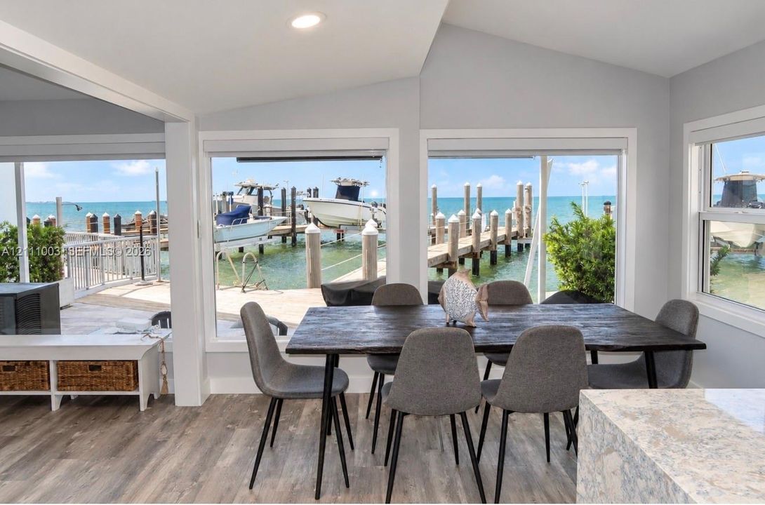 Waterfront dining area featuring floor-to-ceiling windows, wood-finish flooring, recessed lighting, and direct access to a private dock