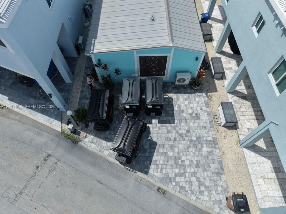 Paver-stone driveway featuring a multi-vehicle parking area, metal roofing, and structured exterior siding