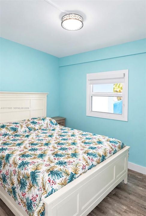 Wood-finish flooring, white window trim, and a decorative circular ceiling light fixture