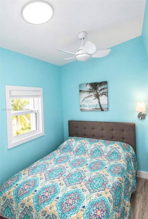 Single-pane window with white trim, white ceiling-mounted flush light fixture, and three-blade white ceiling fan with integrated lighting