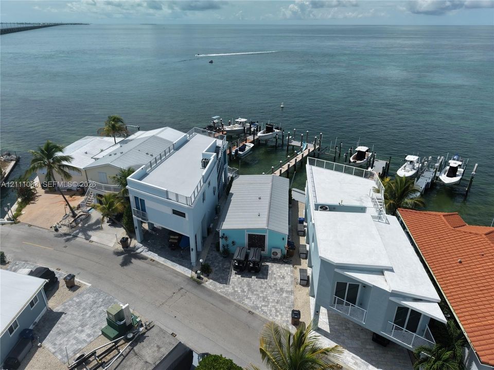 Waterfront property featuring a private boat dock, multi-level structures with rooftop decks, and paver driveways situated on the open sea