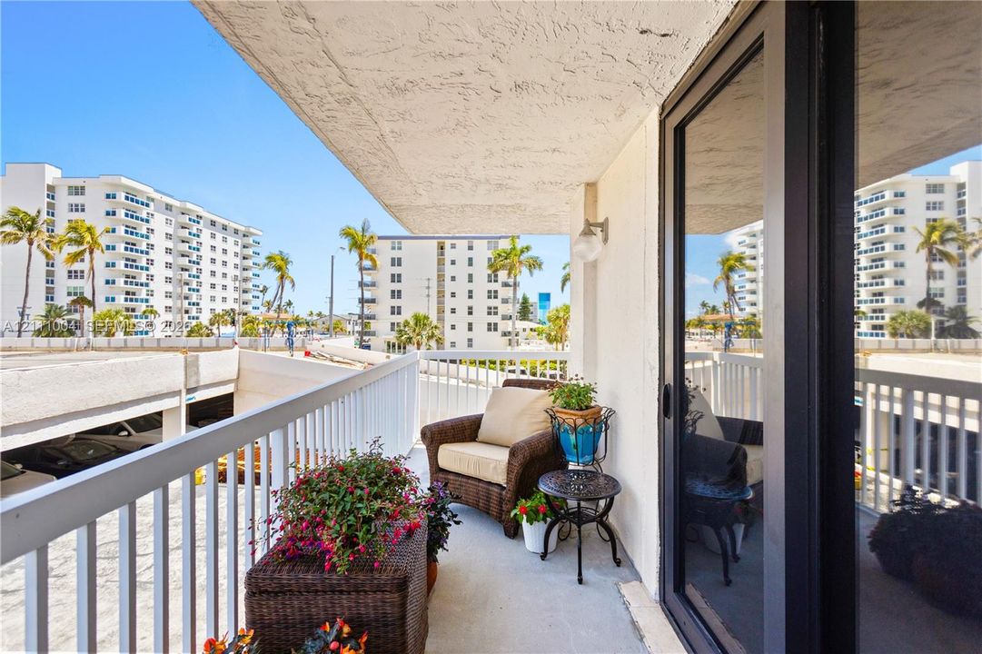 Private balcony featuring white vertical railings and a wall-mounted light fixture, accessible via sliding glass doors