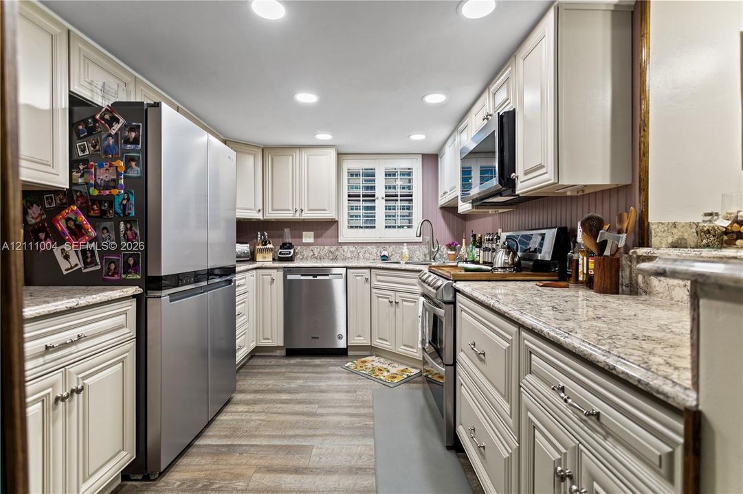Kitchen featuring shaker-style cabinetry, stone countertops, stainless steel appliances, recessed lighting, and wood-finish flooring