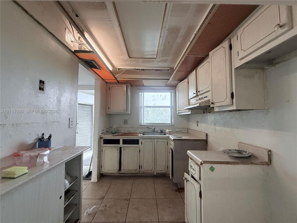 Kitchen featuring white cabinetry, tile flooring, and a single-basin sink