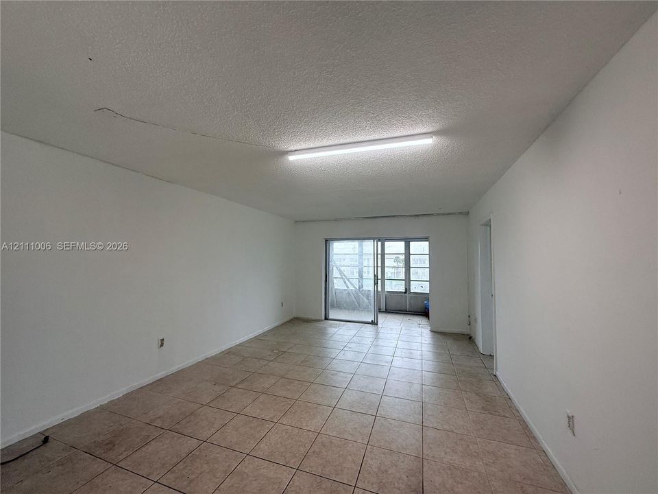 Neutral-toned tile flooring, textured ceiling with linear light fixture, and sliding glass door