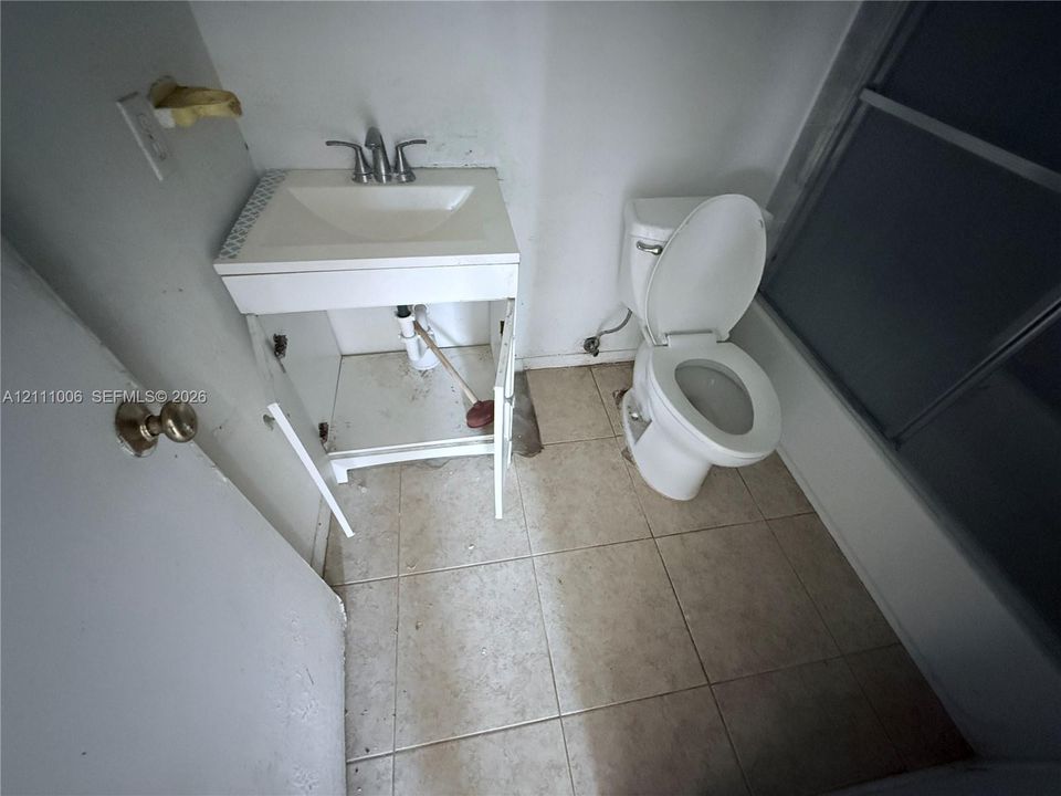 Bathroom featuring a ceramic tile floor, white pedestal-style sink with a dual-handle faucet, and a standard porcelain toilet