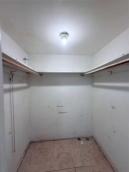Storage area featuring tile flooring, built-in shelving, and dual hanging rods