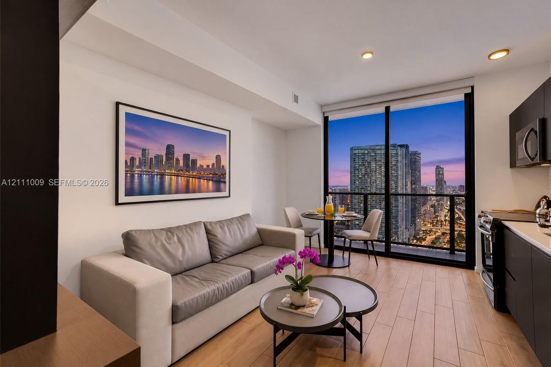 Floor-to-ceiling windows, wood-finish flooring, recessed lighting, and kitchen cabinetry with a matte finish