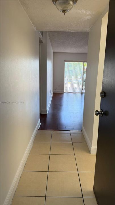 Entryway featuring neutral-toned tile flooring, wood-finish flooring, and sliding glass doors