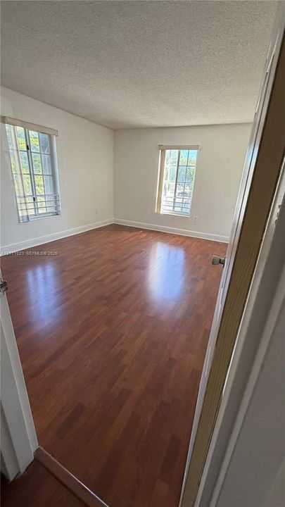 Interior room featuring wood-finish flooring, white walls, and two windows with multi-pane grid detailing
