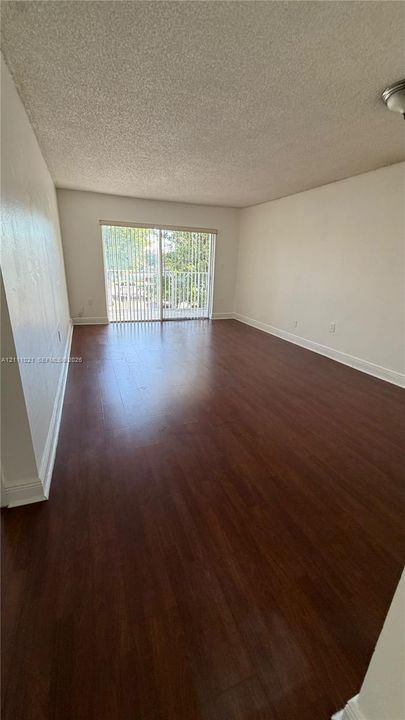 Wood-finish flooring, neutral wall tones, and a sliding glass door providing external access