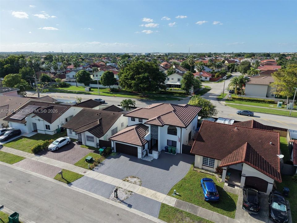 Two-story residence featuring a multi-pitched tile roof, paved driveway, and stone veneer accents