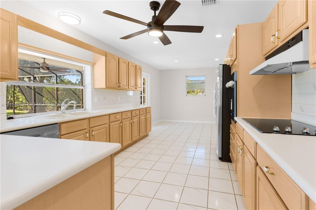Kitchen featuring light-finish cabinetry, white solid-surface countertops, tile flooring, recessed lighting, and a ceiling fan