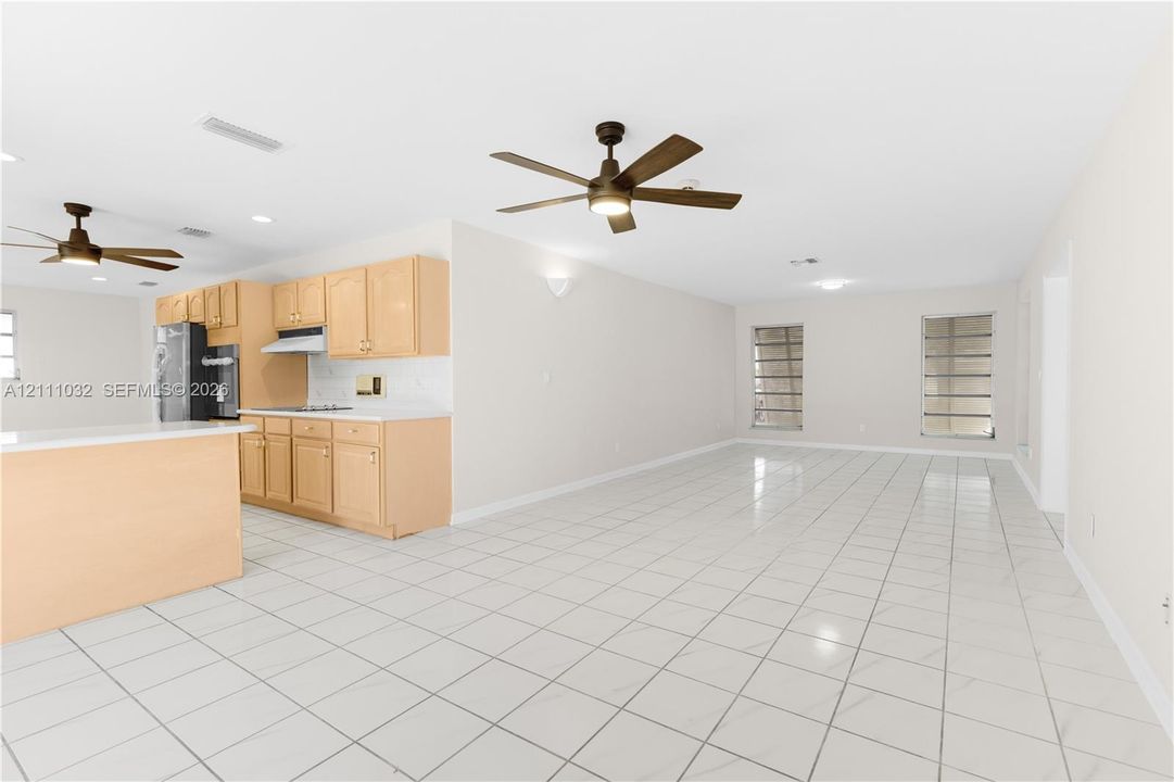 Kitchen featuring light wood cabinetry, white countertops, and white tile flooring