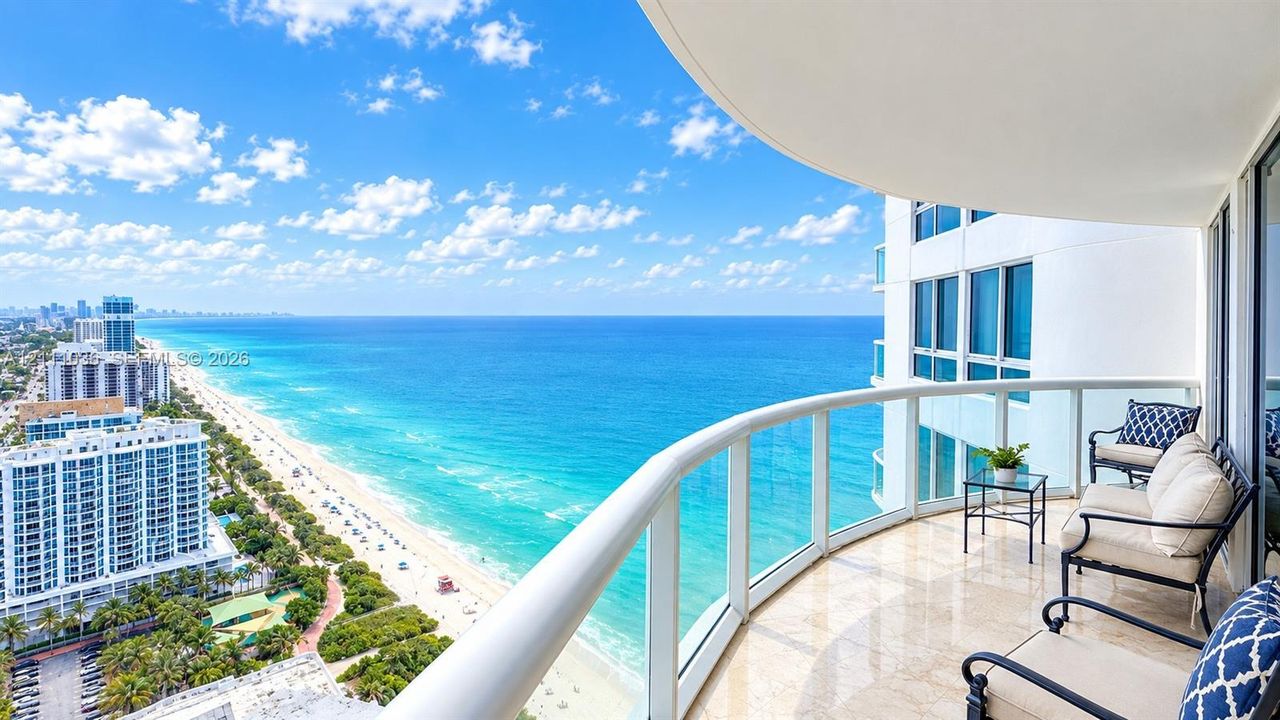 Covered balcony featuring natural stone flooring, glass panel railings, and expansive ocean scenery