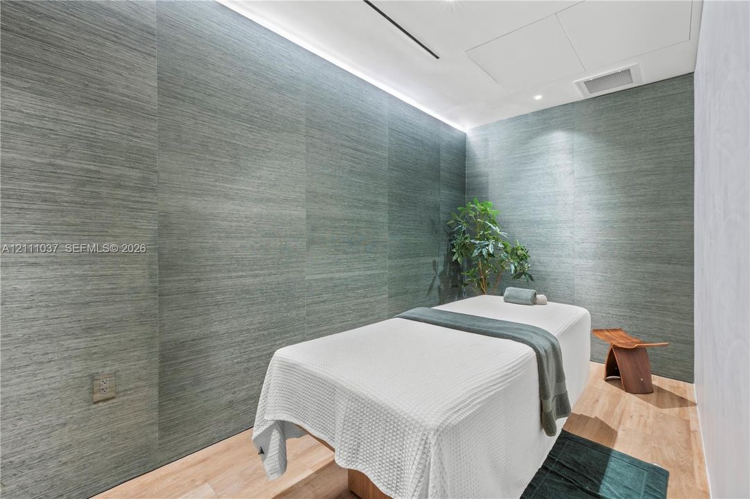 Textured wall paneling, integrated cove lighting, and light-toned wood-finish flooring