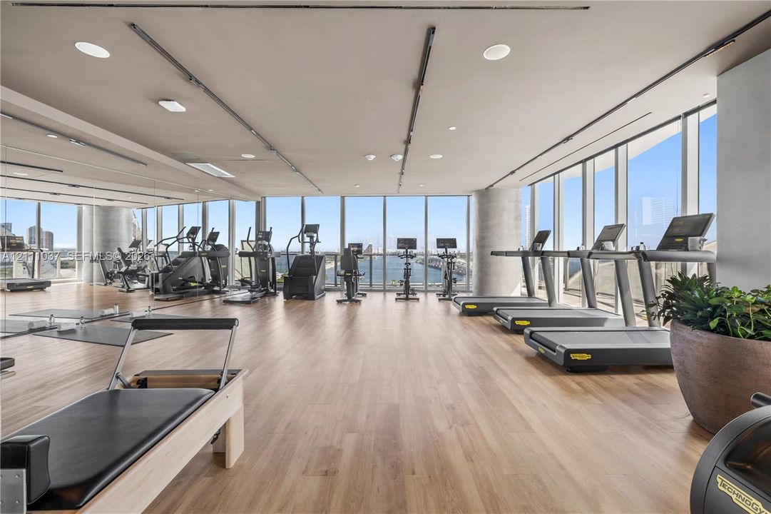 Fitness center featuring expansive floor-to-ceiling windows, wood-finish flooring, recessed lighting, and wall-mounted track lighting