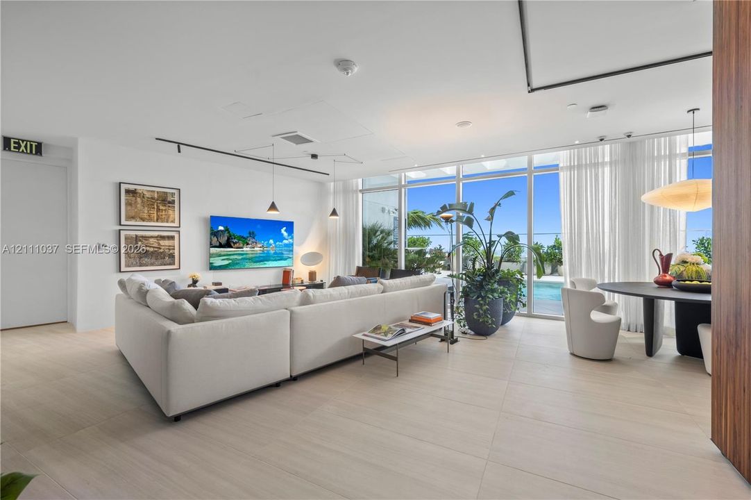 Open-concept interior featuring floor-to-ceiling glass walls, large-format tile flooring, recessed lighting, and integrated track lighting