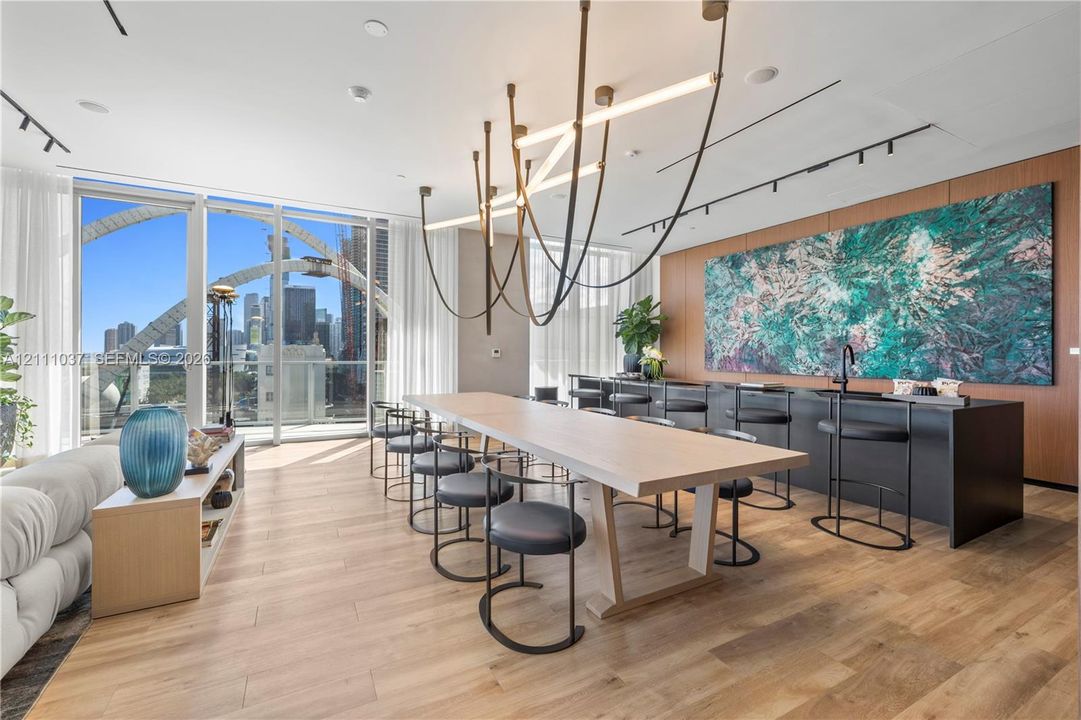 Floor-to-ceiling windows, wood-finish flooring, linear track lighting, sculptural chandelier, and built-in matte black cabinetry