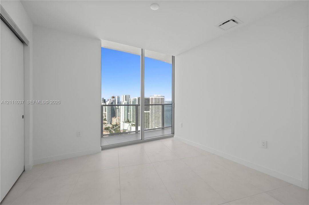 Floor-to-ceiling windows, large-format tile flooring, and integrated glass-panel balcony
