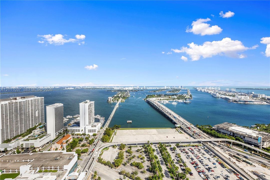 Elevated coastal perspective featuring expansive water horizons, bridge infrastructure, and metropolitan skyline silhouettes