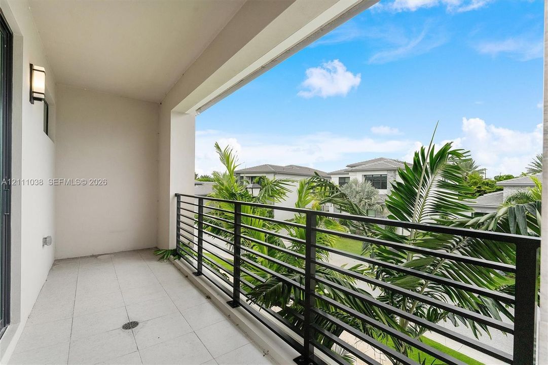 Covered balcony featuring tile flooring, metal railing, and wall-mounted exterior lighting
