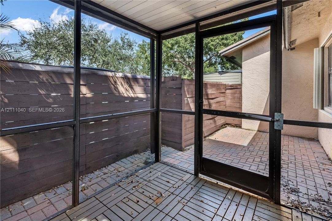 Screened-in enclosure featuring a wood-plank floor, paver patio, and horizontal wood privacy fencing