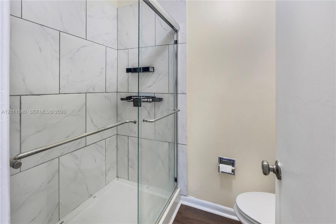 Walk-in shower featuring glass enclosure, large-format tile surround, integrated shower shelving, and polished metal hardware