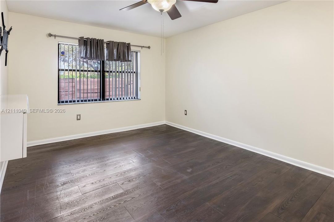 Neutral wall finishes, wood-finish flooring, and a ceiling-mounted fan with integrated lighting