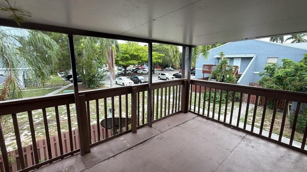 Covered balcony featuring wood-tone railings and solid surface flooring