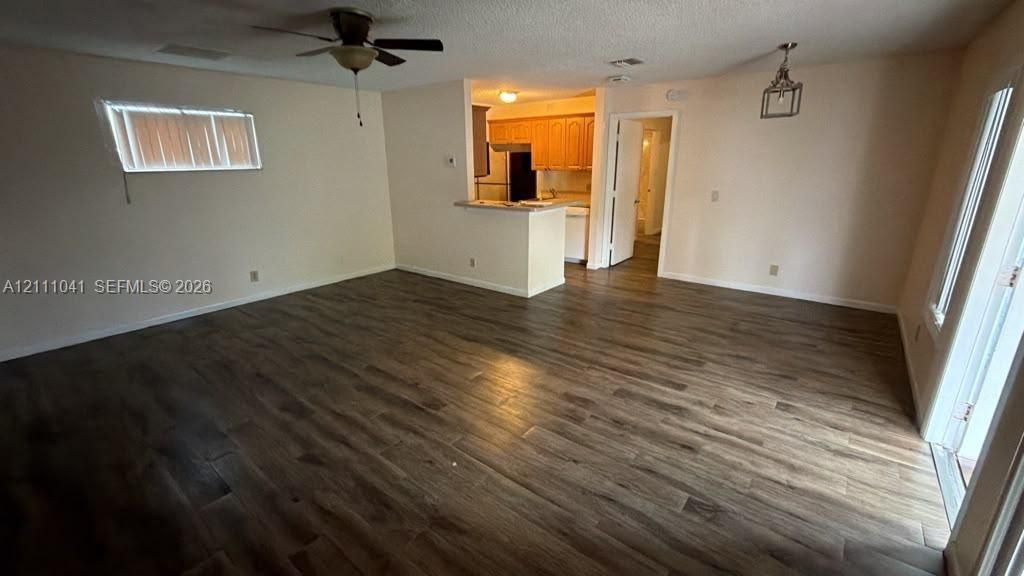 Living area featuring wood-finish flooring, a ceiling fan, a kitchen pass-through counter, and recessed lighting