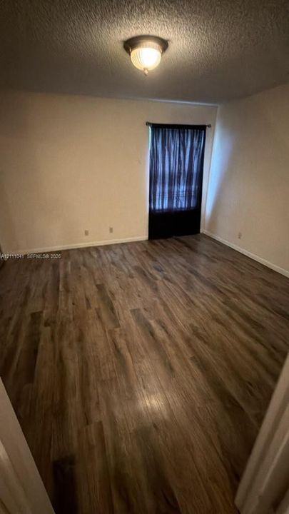 Wood-finish flooring, neutral walls, and a dome-style ceiling light fixture