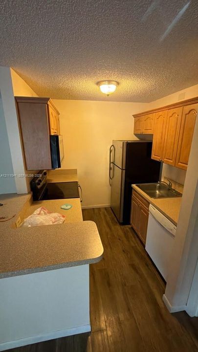 Kitchen featuring wood-finish cabinetry, solid-surface countertops, wood-finish flooring, and built-in appliances