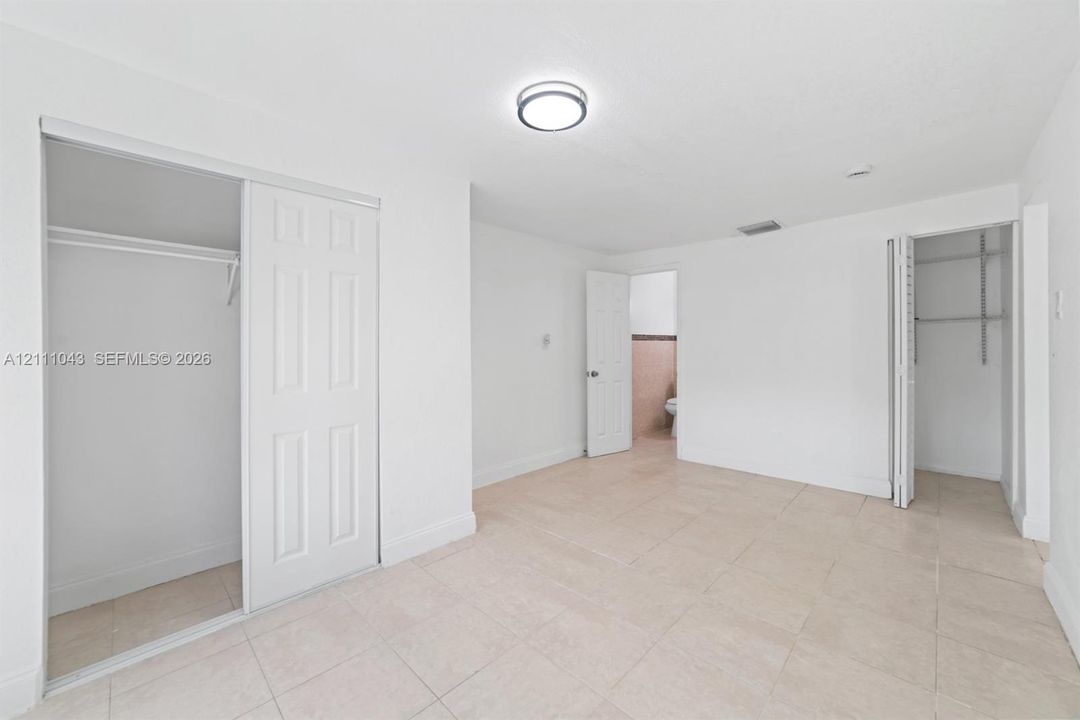 Neutral-toned ceramic tile flooring, dual closets with sliding paneled doors, and flush-mount ceiling lighting