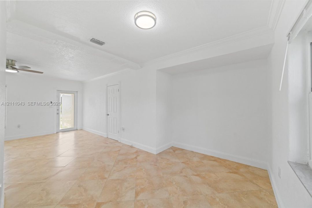 Neutral-toned tile flooring set in a diagonal pattern, recessed ceiling fixture, crown molding, and a multi-panel door