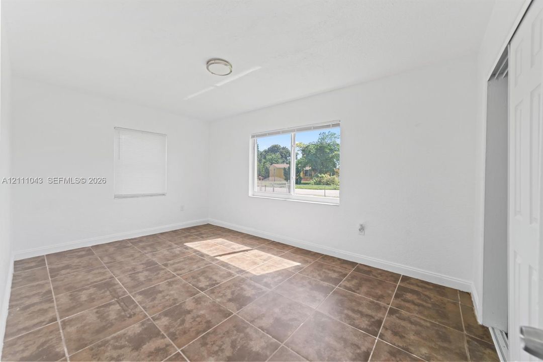 Interior room featuring tile flooring, neutral walls, two windows with blinds, and a built-in closet with double-panel doors