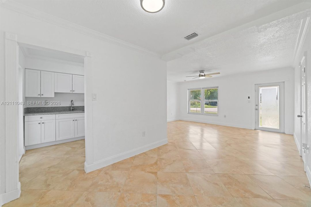 Ceramic tile flooring, white shaker-style cabinetry, neutral stone-finish countertops, and dual ceiling fans