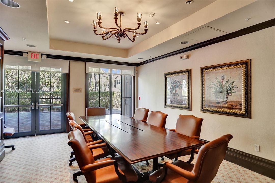 Conference room featuring a tray ceiling, decorative metal chandelier, crown molding, and floor-to-ceiling glass-paned doors