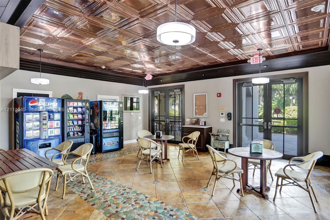 Interior space featuring a decorative copper-toned coffered ceiling, tile flooring with mosaic accent inlay, dual sets of glass-paned double doors, and crown molding