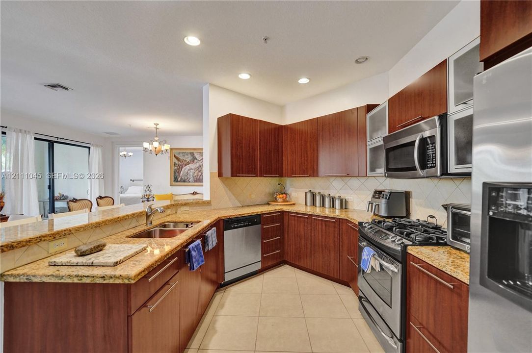 Kitchen featuring flat-panel wood cabinetry, stone countertops, tiled backsplash, stainless steel appliances, and recessed lighting