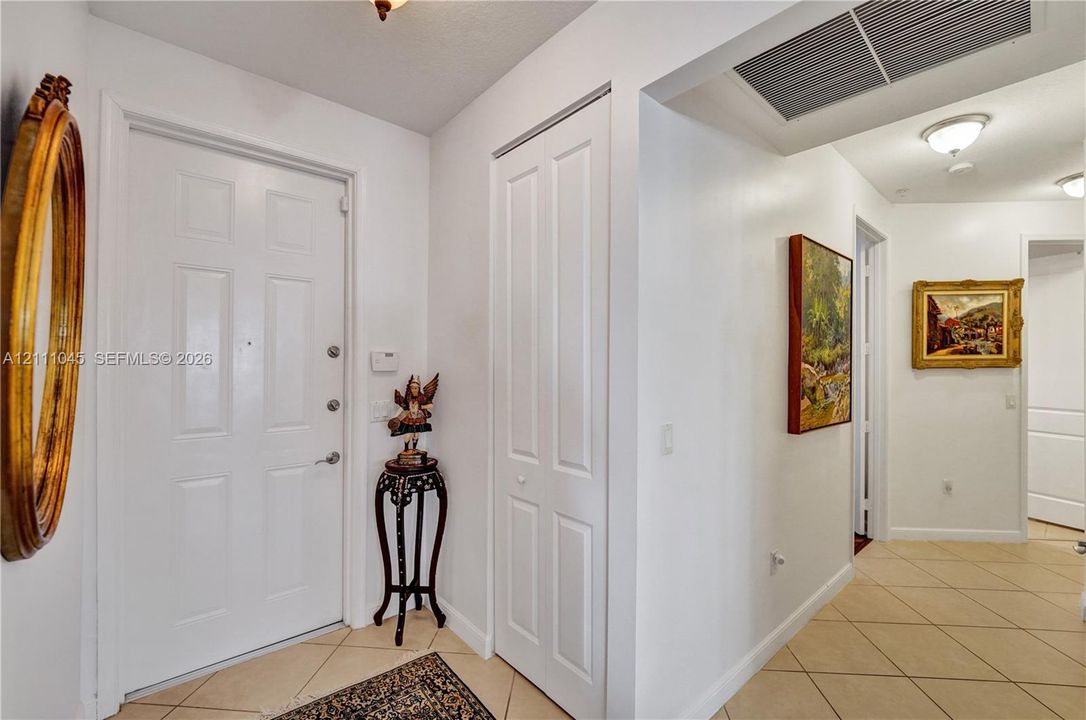 Entry foyer featuring a white paneled door, ceramic tile flooring, and closet with white bi-fold doors, accented by ceiling-mounted lighting