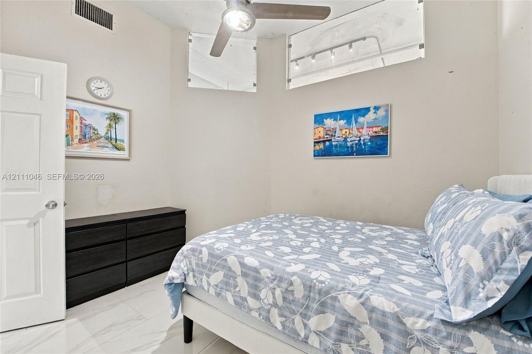 High-ceiling room featuring large clerestory windows, overhead ceiling fan with integrated lighting, recessed track lighting, and polished tile flooring