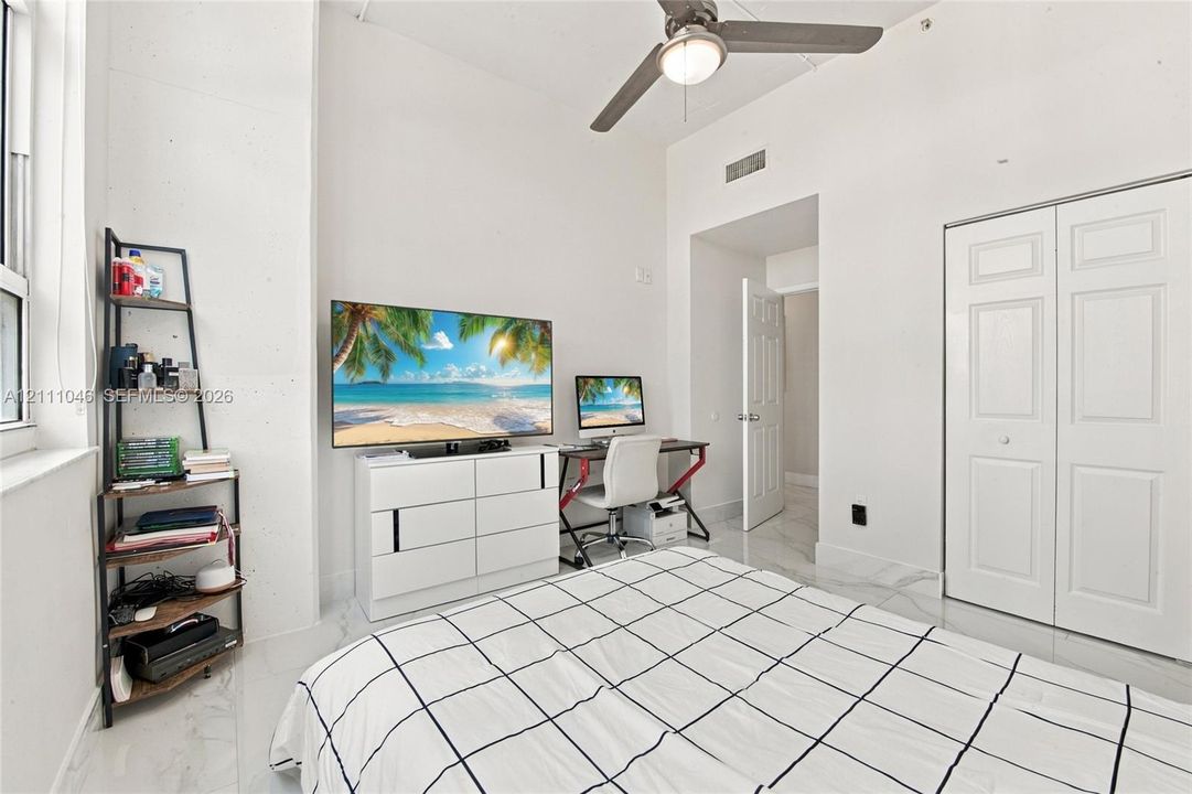 Room with high ceilings, stone-finish flooring, ceiling fan with integrated lighting, and a double-door closet