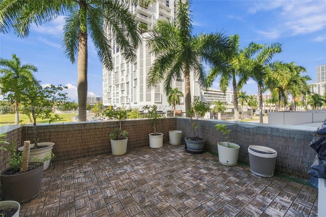 Private outdoor balcony featuring modular wood-tile decking and a textured masonry perimeter wall