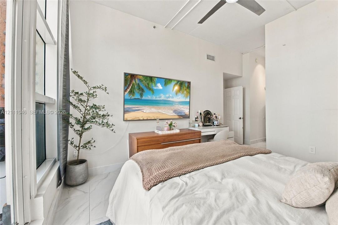High ceilings featuring a modern ceiling fan, floor-to-ceiling windows, and polished stone-finish flooring