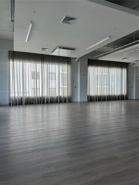 Expansive open-concept interior featuring wood-finish flooring, floor-to-ceiling windows, and recessed ceiling lighting