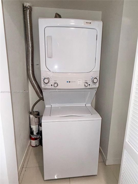 Stacked white washer and dryer unit with top-loading washing machine and front-loading dryer
