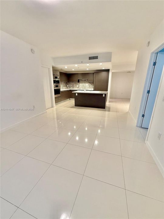 Kitchen featuring flat-panel cabinetry, an island with countertop seating, stone backsplash, and recessed lighting, finished with high-gloss tile flooring