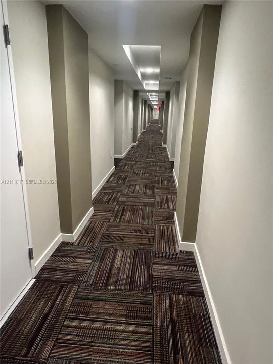 Hallway featuring recessed ceiling lighting, textured wall-to-wall carpeting, and neutral wall tones