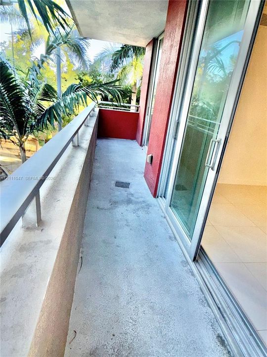 Private balcony with concrete flooring, metal railing, and floor-to-ceiling glass sliding doors